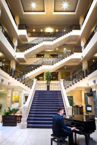 a man sitting at a piano in a building with stairs at The Heritage in Killenard