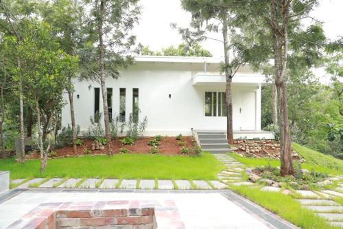 a white house with trees in front of it at Blue Valley Estate - Mountain View Villa in Yercaud