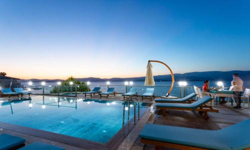 a pool at a hotel with people sitting at a table at Güllük Yalı Boutique Otel in Gulluk