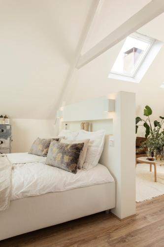 a white bed in a white room with a window at Huize Copes apartment Den Haag, 2 bed, 2 bath in The Hague