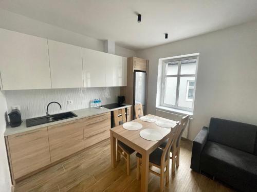 una cocina con mesa y sillas y una cocina con armarios blancos. en Apartamenty Sokola en Lodz