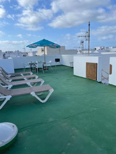 patio z krzesłami i parasolem na dachu w obiekcie apartamento anzuelo w mieście Famara