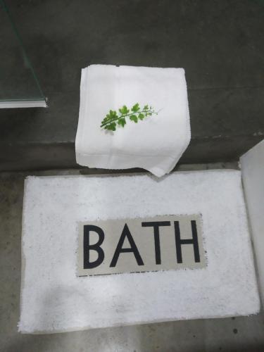 a white rug with the word bath with a towel at Acacia Inn GuestHouse in Maputo