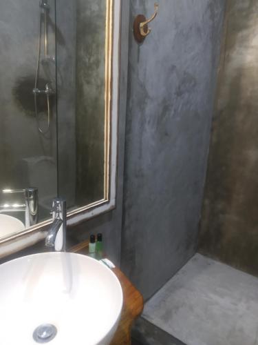 a bathroom with a sink and a shower with a mirror at Acacia Inn GuestHouse in Maputo
