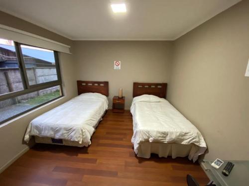 two beds in a room with a window at Hotel San Martin in Cabrero