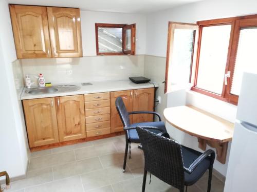 a kitchen with wooden cabinets and chairs and a table at Sobe i apartmani Simic in Ribarska Banja