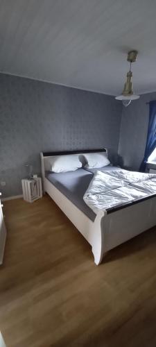 1 dormitorio con cama blanca y pared azul en FeWo Am Marktplatz en Zerf