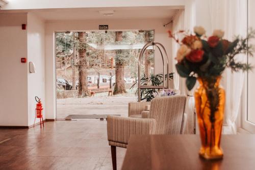 a vase of flowers on a table in a room at Hotel Colina São Francisco in Gramado