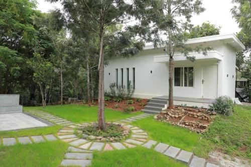 a white house with a tree in the yard at Blue Valley Estate-Mountain View Villa in Yercaud