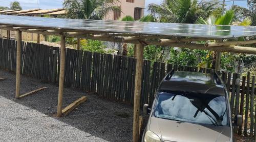 a car parked under a wooden pergola at Pousada Praia das Ondas - Pé na areia in Itacimirim