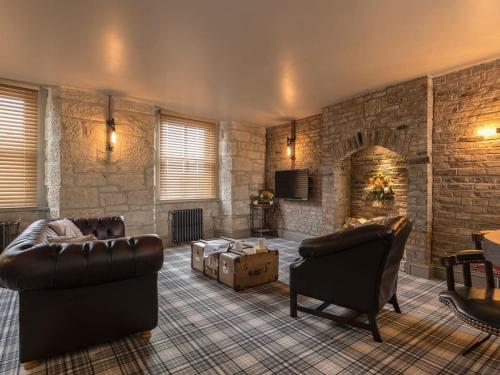 a living room with leather furniture and a stone wall at Newgate Loft in Morpeth