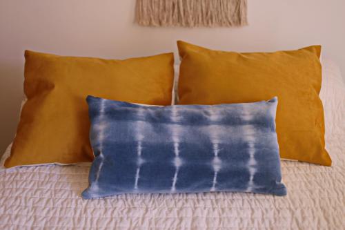 a bed with two pillows and two blue and yellow pillows at CHIVILCOY APART in Chivilcoy