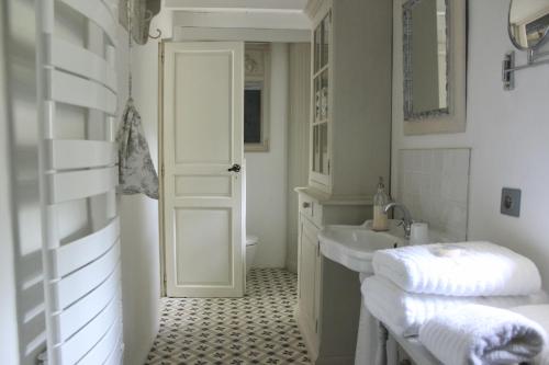 een witte badkamer met een wastafel en een spiegel bij Mas de Rique in Saint-Étienne-du-Grès