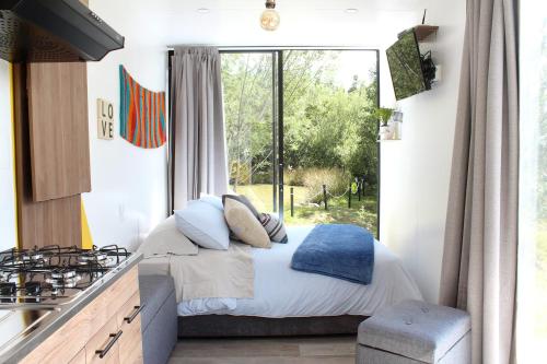 a bedroom with a bed and a large window at Libre Camp Amarillo in Nemocón