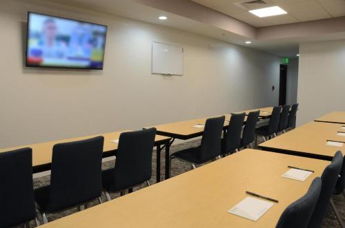 a conference room with tables and chairs and a screen at Staybridge Suites Nashville SE - Murfreesboro by IHG in Murfreesboro