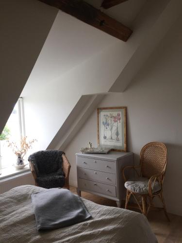 a bedroom with a bed and two chairs and a dresser at Munkagården Bed & Breakfast in Svalöv