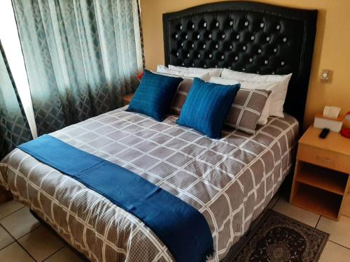 a bedroom with a large bed with blue pillows at TM Self Catering Accommodation in Middelburg