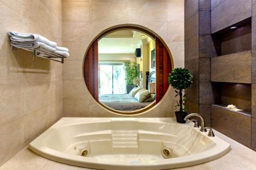 a large tub in a bathroom with a round mirror at Villa Paula Cozumel in Cozumel