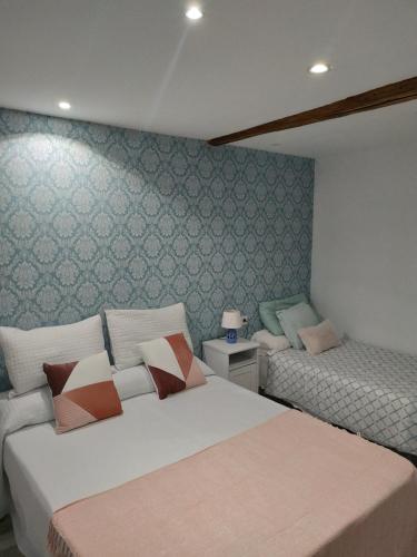 two beds in a bedroom with green wallpaper at RUA NOVA APARTMENT ATICO 3º,a 200m CATEDRAL,PS 4 y NETFLIX in Santiago de Compostela