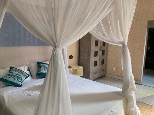 a bedroom with a white canopy bed with blue pillows at Acacia Inn GuestHouse in Maputo