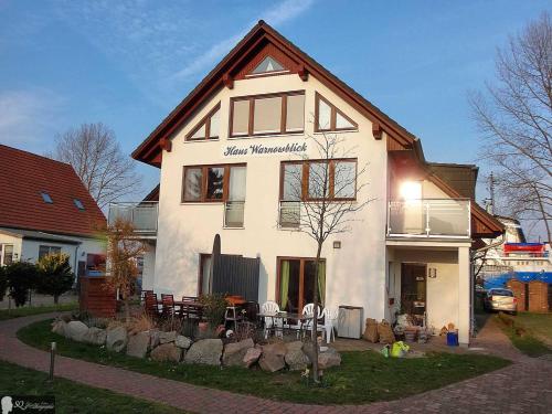 ein weißes Haus mit einem Tisch und Stühlen davor in der Unterkunft Haus Warnowblick Objekt 36737 in Rostock