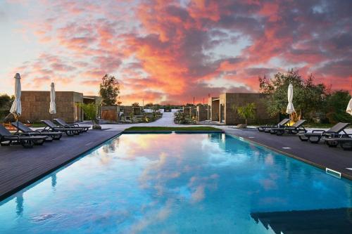 a swimming pool with lounge chairs and a sunset at EcoVillas Escudeira in Reguengos de Monsaraz