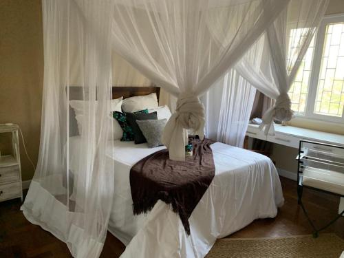 a bedroom with a canopy bed with white curtains at Acacia Inn GuestHouse in Maputo