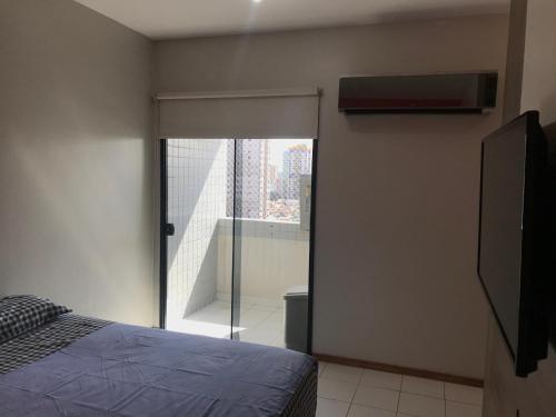 een slaapkamer met een glazen schuifdeur naar een balkon bij Mobiliado e aconchegante in Belém