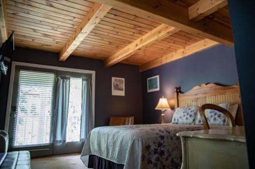 1 dormitorio con cama y techo de madera en Elk River Hotel & Cafe en Sutton