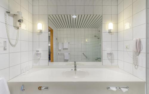 a white bathroom with a sink and a mirror at Soria Moria Hotell in Oslo