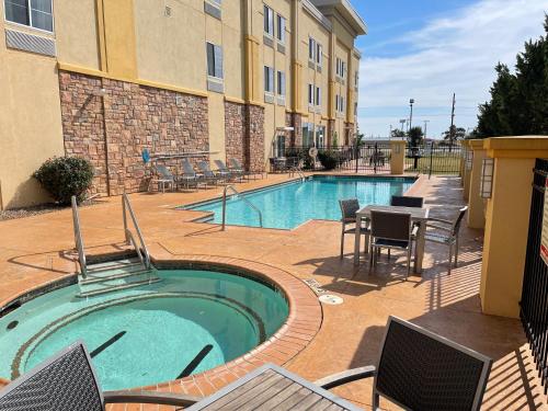 a pool with chairs and a table next to a building at La Quinta by Wyndham Elk City in Elk City