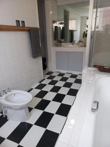 a bathroom with a toilet and a black and white checkered floor at Seaside Getaway @ Swallow House Suite #1 in Cape Town