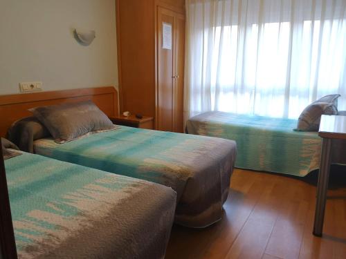 a hotel room with two beds and a window at Hospedaje Covadonga in Gijón