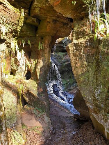 a cave with a waterfall in a rocky cliff at Cosy wood cabin in rural area near national park in Cumnock