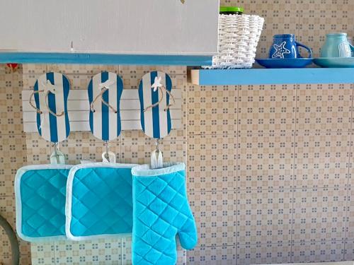 a pair of blue oven mitts hanging on a wall at VISTA MARE Su tre piani con giardino in Falerna