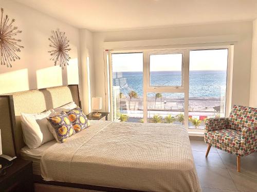 Schlafzimmer mit einem Bett und Meerblick in der Unterkunft Ocean View Condo overlooking the Caribbean Sea in Oranjestad