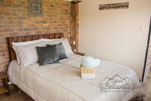 a bed in a bedroom with a brick wall at Cabaña Bellavista in Iza