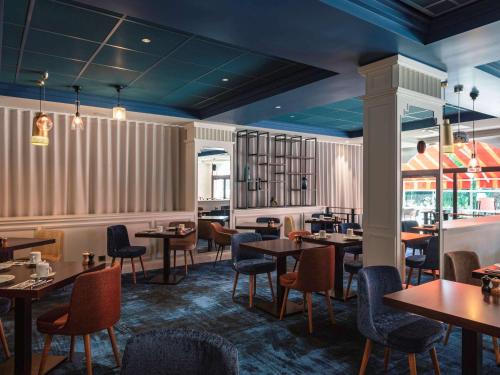 a dining room with tables and chairs and windows at ibis Styles Aix les Bains Domaine de Marlioz in Aix-les-Bains