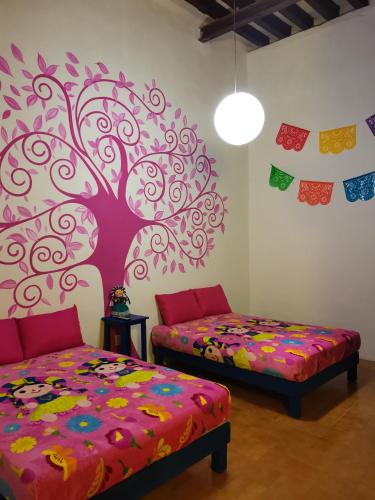 a bedroom with two beds and a tree mural at Lele y Panchito en el Centro in Querétaro