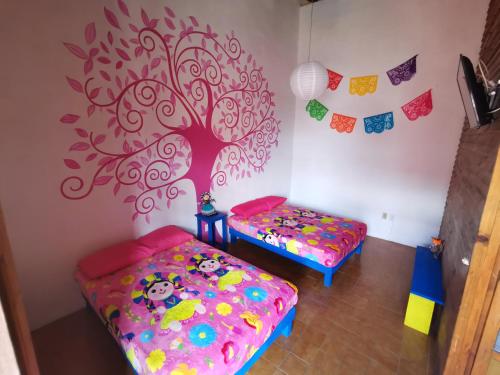 a room with two beds and a tree on the wall at Lele y Panchito en el Centro in Querétaro