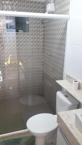 a bathroom with a toilet and a glass shower at Casa temporada Condomínio fechado Praia de Barramares in Ilhéus