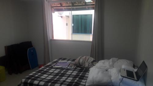 a bedroom with a bed with two laptops and a window at Casa temporada Condomínio fechado Praia de Barramares in Ilhéus