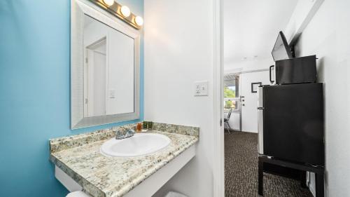 W łazience znajduje się umywalka, lustro i lodówka. w obiekcie Grand Traverse Motel w mieście Traverse City
