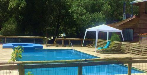 a swimming pool with a gazebo next to a house at Cabañas Lihuén SPA in Parral