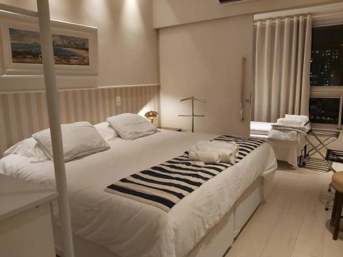 Un dormitorio con una gran cama blanca y una ventana en Residencial Portal da Barra, en Río de Janeiro