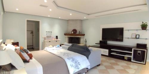 a large living room with a couch and a television at Casa Verde - Suíte 1 in Teresópolis