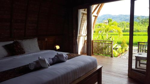 a bedroom with a bed with a view of a yard at Umma Bali Menjangan Retreat in Banyuwedang