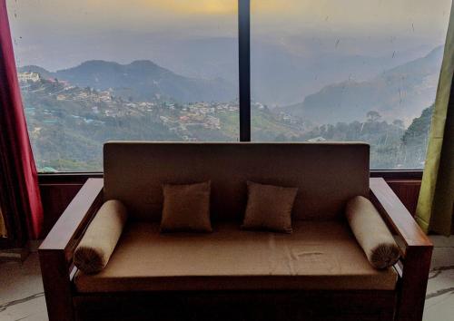 a couch sitting in front of a large window at Casa Arhan 2-3-4-7-12 BHK Luxury Penthouse in Mussoorie