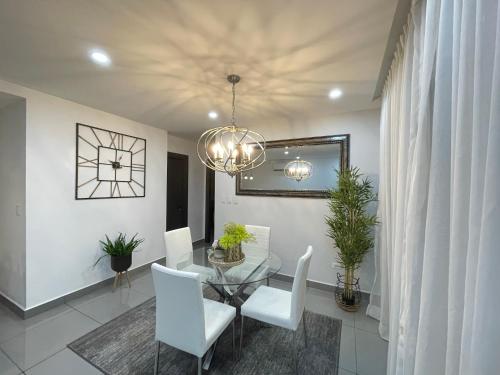 a dining room with a glass table and white chairs at Fino y Elegante Condominio Ejecutivo in San Pedro Sula