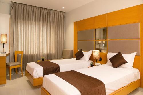 a hotel room with two beds and a desk at Sri Aadhish Grand Hotel in Arantāngi